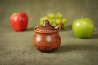 Handmade clay salt bowl with lid and spoon, artisan ceramic homeware on table with fruit