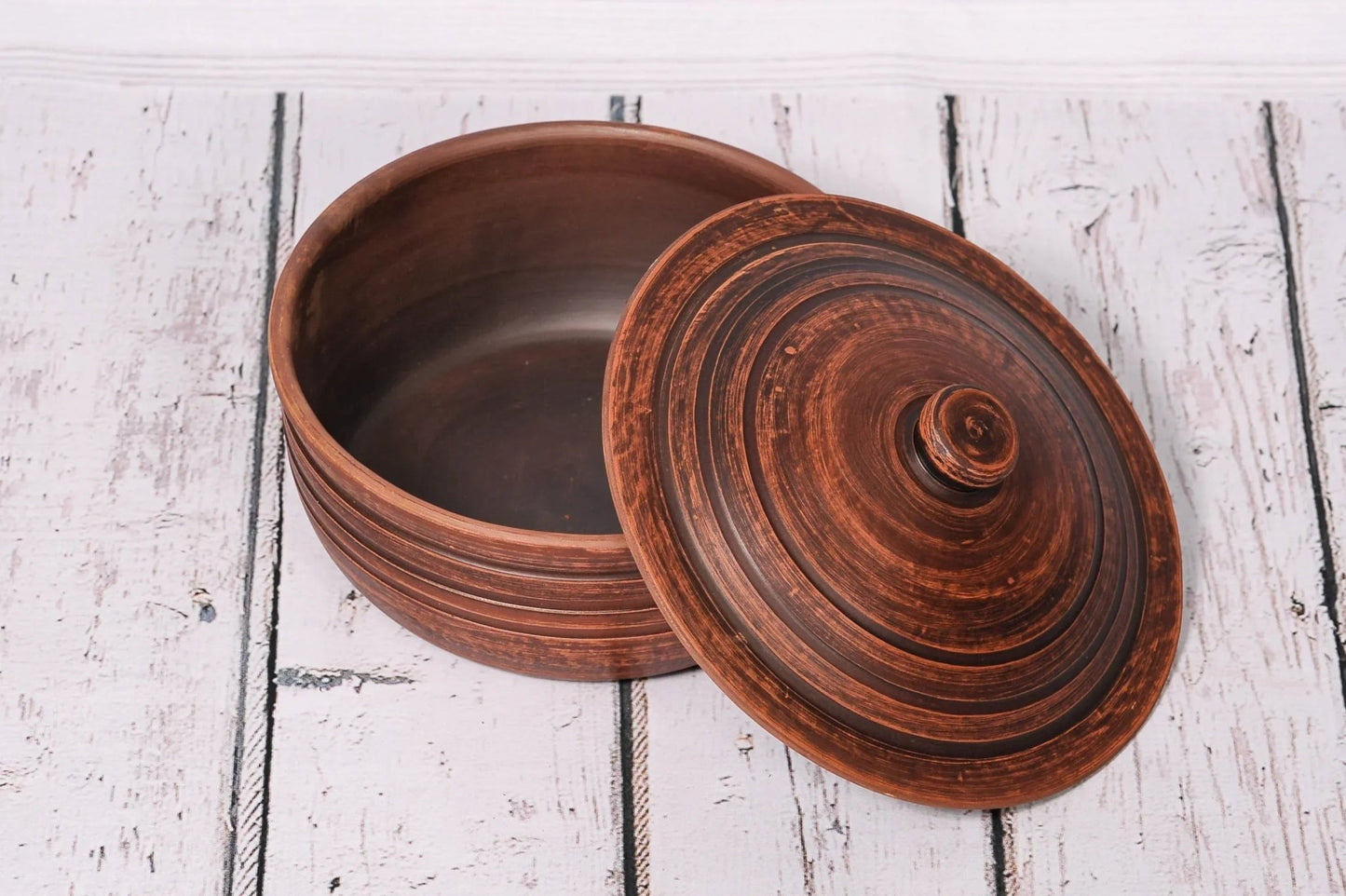 Handmade clay ceramic baking dish with lid on rustic wooden background, artisan homeware