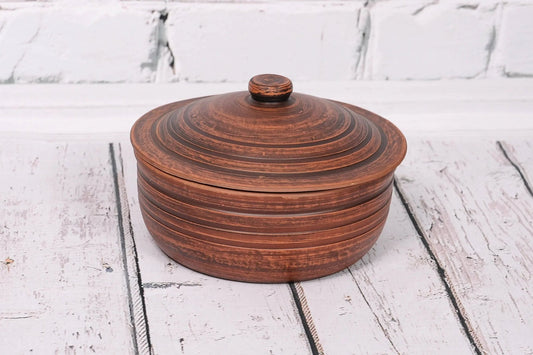 Handmade clay ceramic baking dish with lid on white rustic wooden table