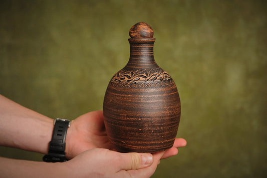 Hand holding a handmade red clay bottle with carved pattern, artisan homeware from clayproductsshop