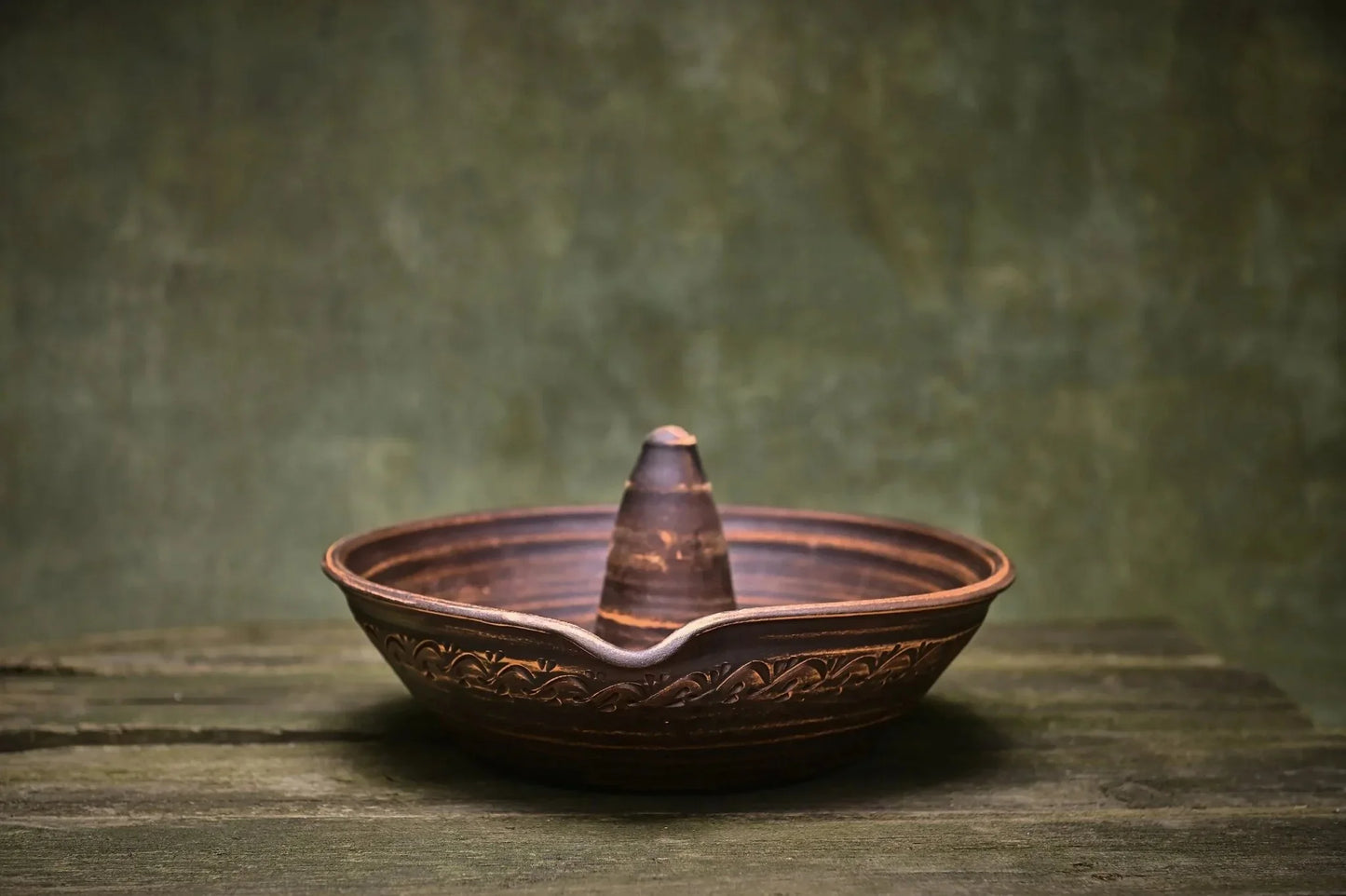 Handmade unglazed ceramic chicken roaster plate on rustic wooden surface