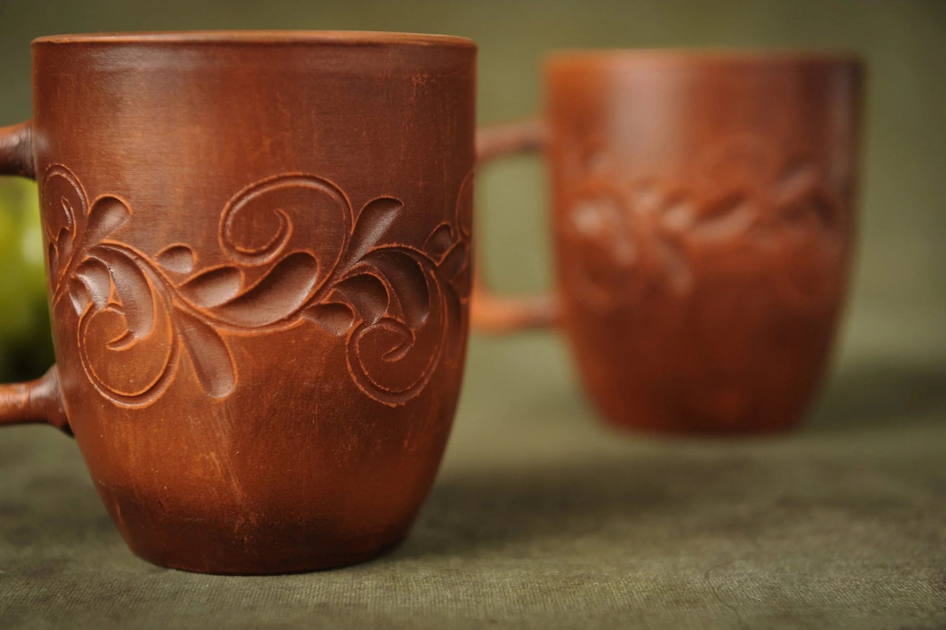 Set of two handmade red clay ceramic cups with carved floral patterns, artisan homeware