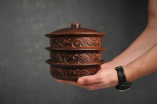 Hand holding set of 3 ornate brown clay ceramic pots with lid, artisan homeware