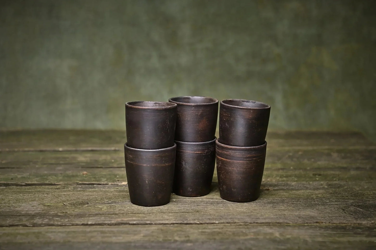 Set of 6 handmade ceramic clay shot glasses on rustic wooden surface, artisan homeware