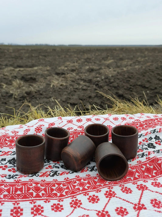 Set of six handmade clay shot glasses on embroidered cloth, artisan homeware decor