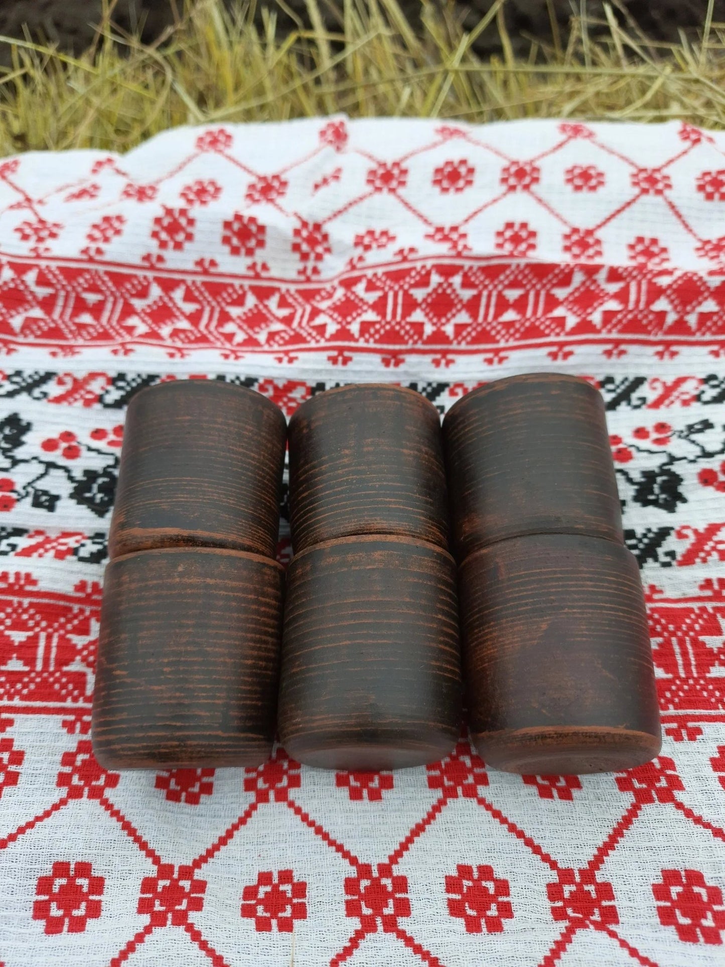 Set of four handmade clay shot glasses on a red and white patterned cloth, rustic design
