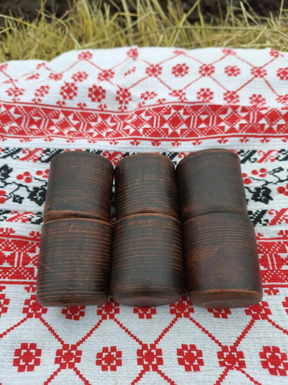 Set of four handmade clay shot glasses on a red and white patterned cloth, rustic design