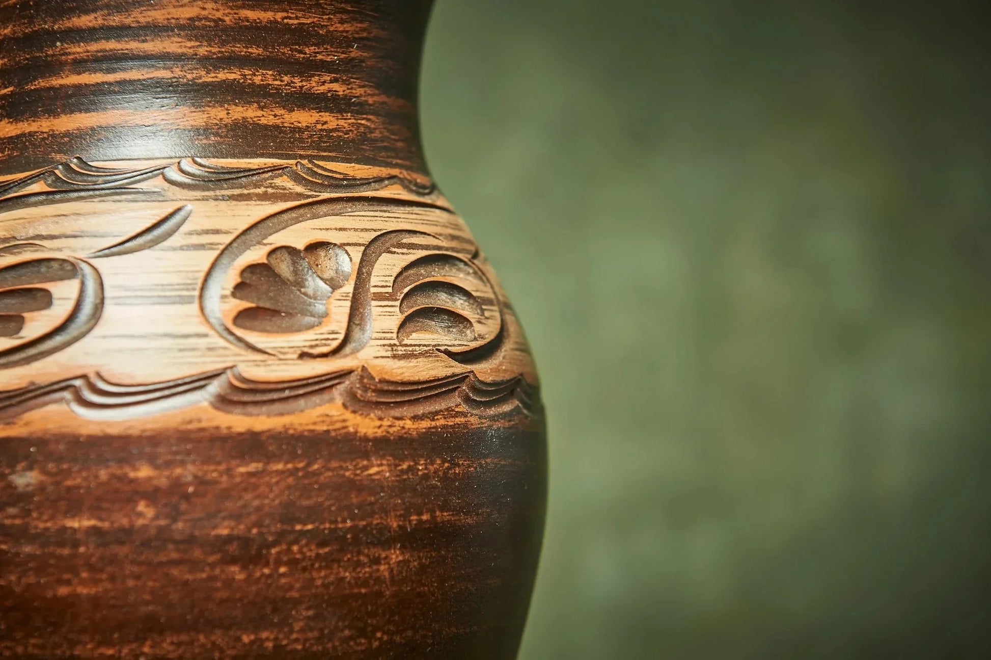 Close-up of handmade clay pottery jug with carved decorative pattern, rustic brown finish