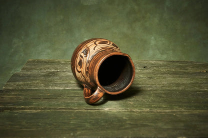 Handmade ceramic clay pitcher with rustic patterns on wooden surface, farmhouse décor