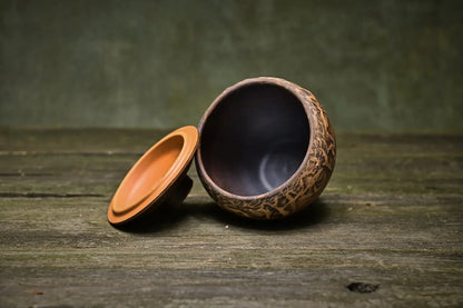Handmade small ceramic pot with lid, rustic Ukrainian pottery on wooden surface