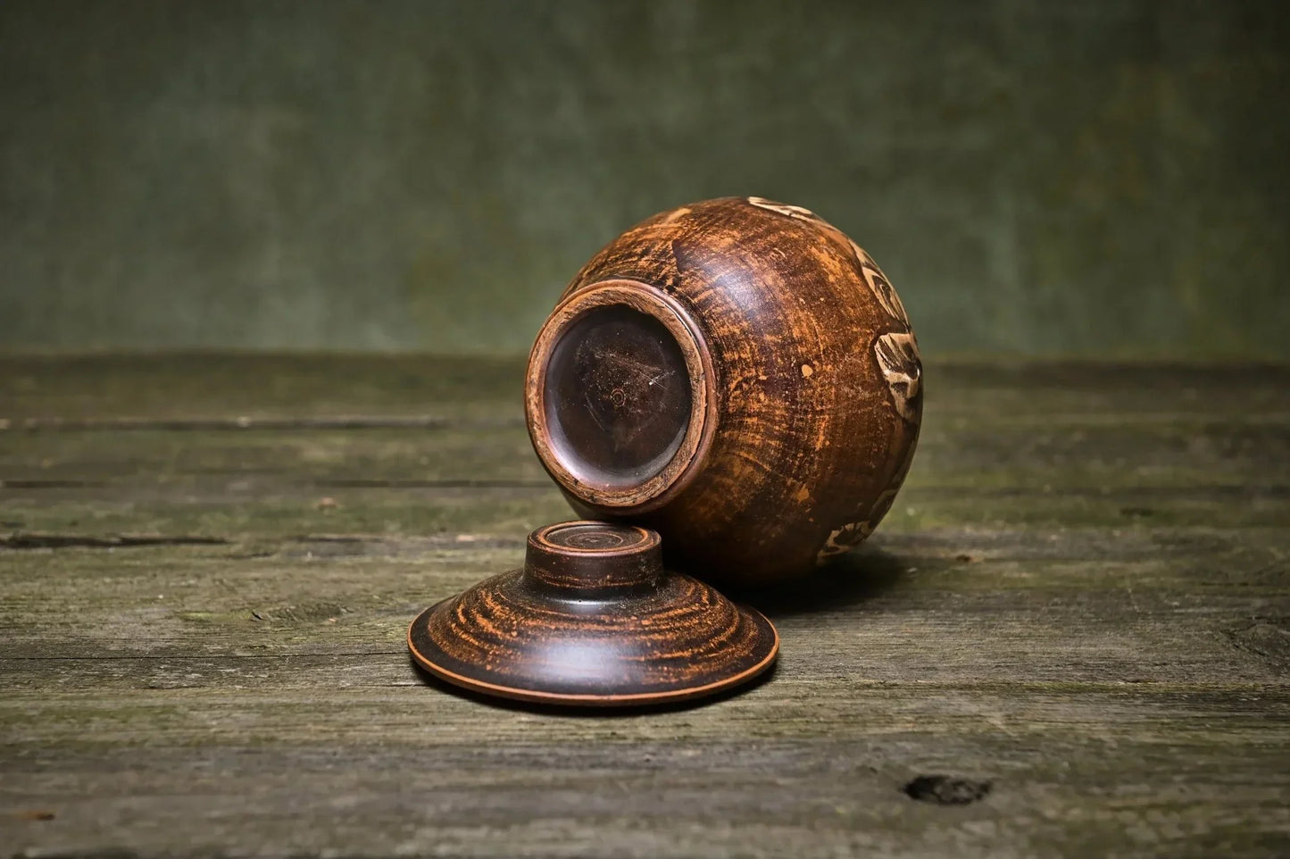 Handmade brown ceramic pot with lid, rustic Ukrainian pottery on wooden surface