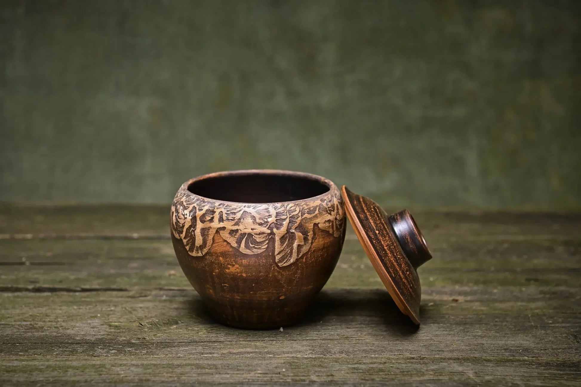 Handmade small ceramic pot with lid, rustic Ukrainian clay bakeware on wooden surface