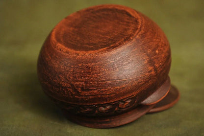 Handmade brown ceramic pot with lid, artisan clay homeware on green background