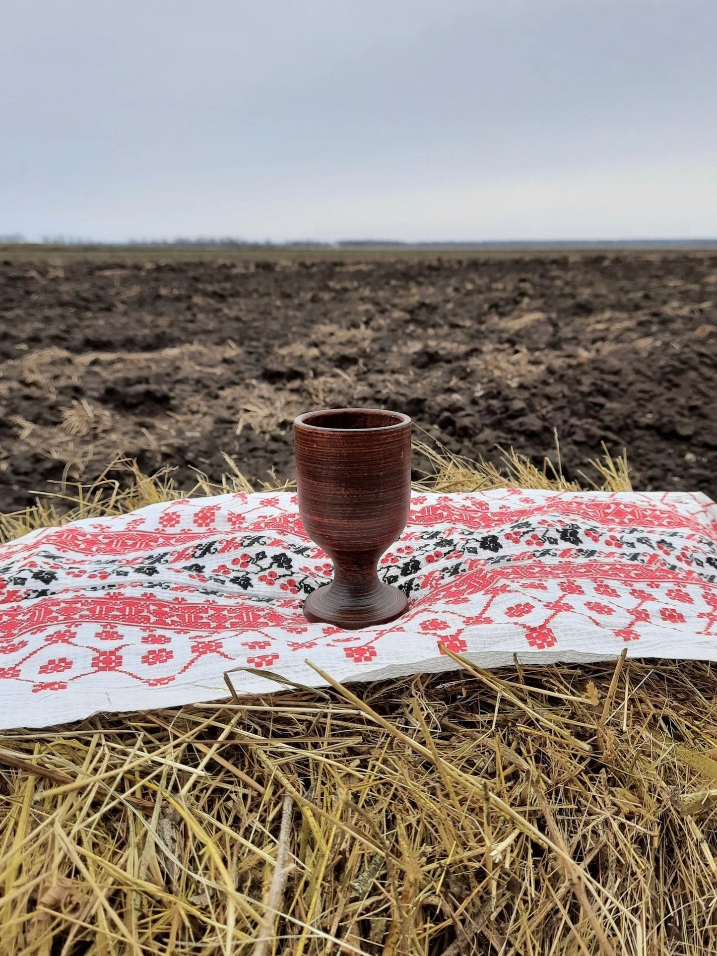 Handmade clay wine glass on embroidered cloth outdoors, artisan homeware by clayproductsshop