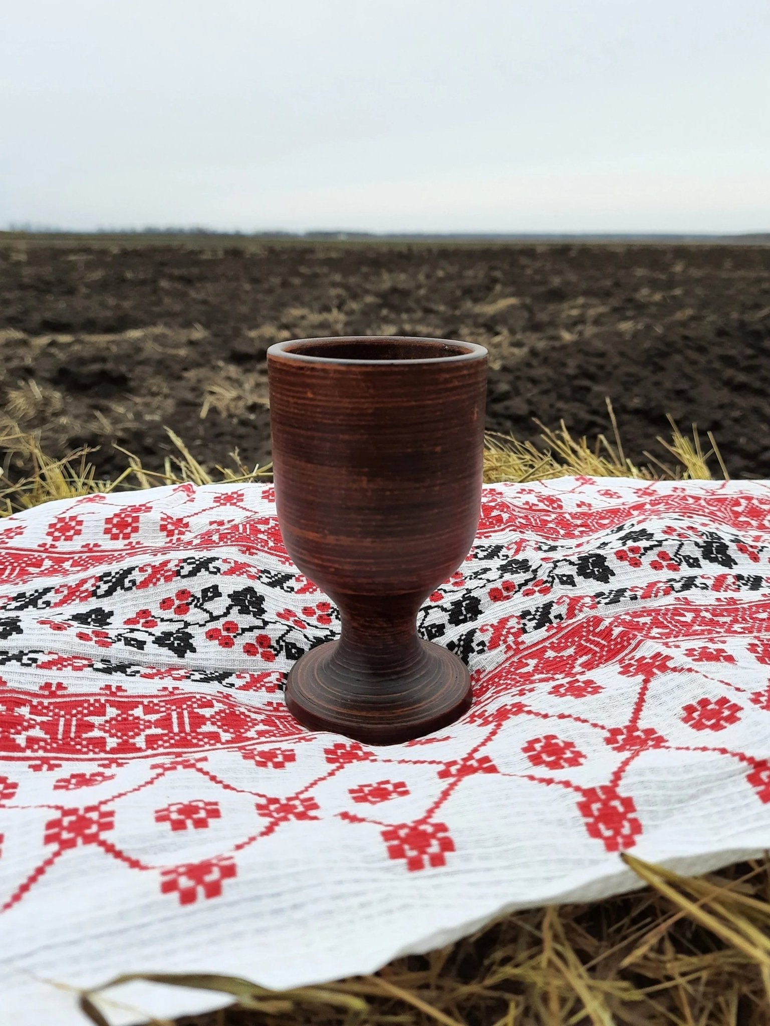 Handmade clay wine glass on embroidered cloth, artisanal homeware by clayproductsshop